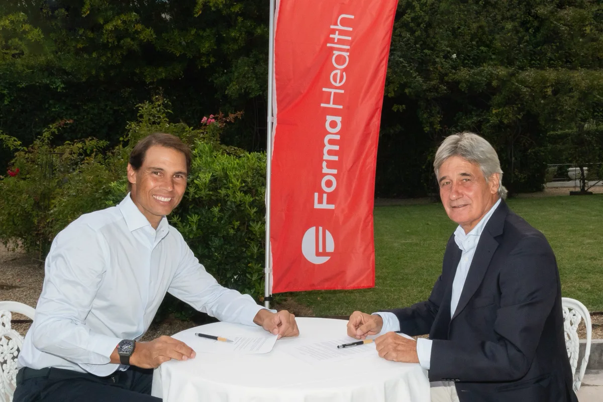 Rafa Nadal y el Dr. Ángel Ruiz-Cotorro firman el acuerdo junto a la banderola de Forma Health